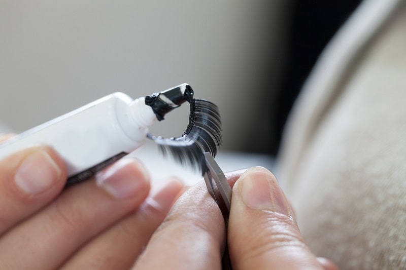 close-up of a woman's hands preparing false eyelashes with cosmetic glue