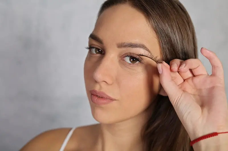 young woman applying fake eyelashes