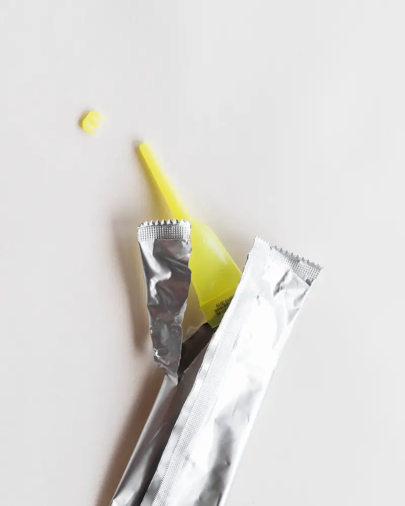 close-up of a used tube of super glue with silver packaging on white background