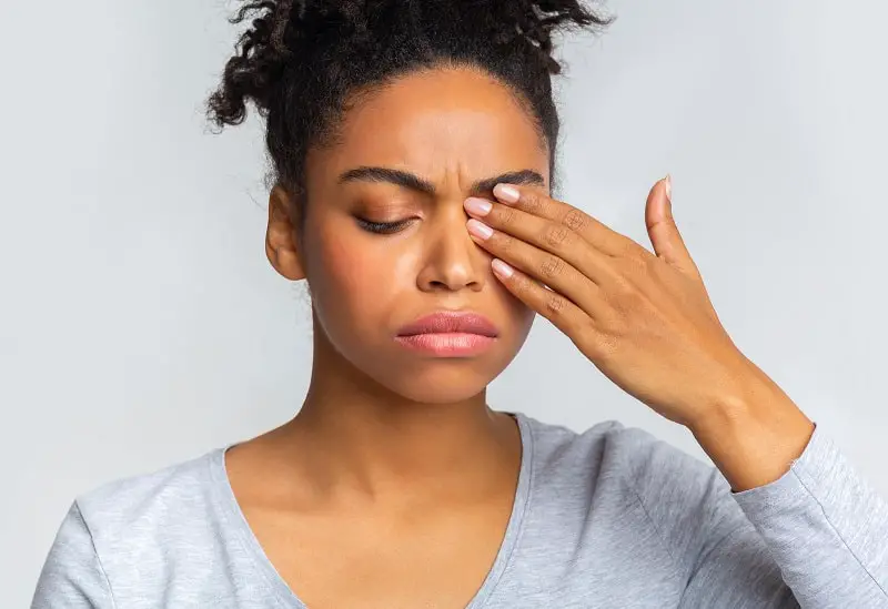black girl touching her eye, suffering from a stye