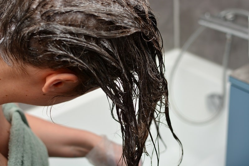 close-up of a young woman dyeing wet hair at home in her bathroom