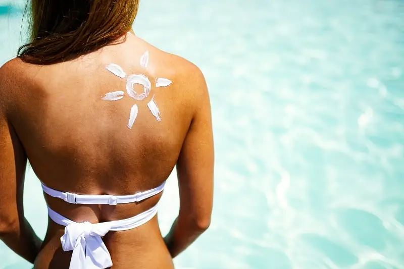 attractive woman with a suntan applying sunscreen against sunburn