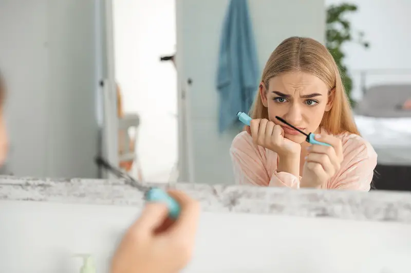 young woman with eyelash loss problem applying mascara