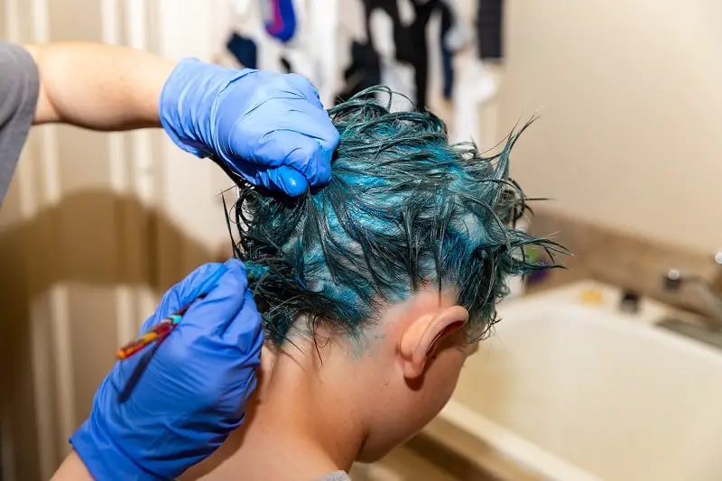 young school student having fun bright blue color hair dye applied to her hair